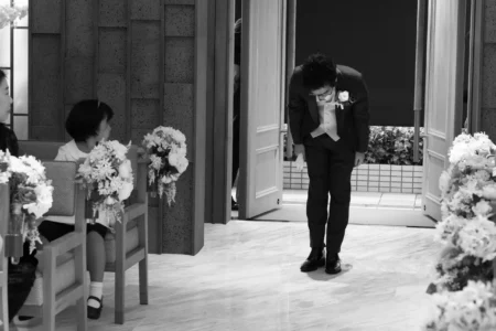 The groom bows before walking down the church aisle at the start of the wedding ceremony. Groom walking down the aisle during his church wedding ceremony in Osaka, Japan.