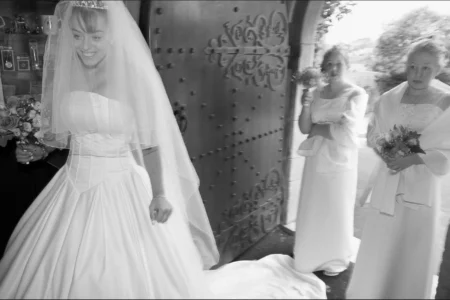 The bride enters the church beaming with joy, bouquet in hand. Bride entering the church holding her bouquet with an excited expression.