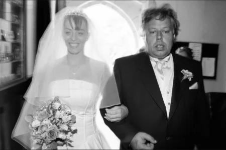 The bride begins her walk down the aisle with her father. Bride walking down the church aisle with her father during the wedding ceremony.