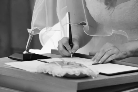 The bride signs the wedding register, a small formal detail within the ceremony. Bride signing the wedding register during her church wedding in Osaka, Japan.