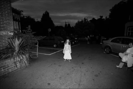 A young guest take a quieter moment outside after the ceremony and reception celebrations. Wedding guests relaxing outside the reception venue on a warm evening.