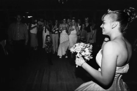 The bride prepares to toss her bouquet to the waiting guests. Bride preparing to toss her bouquet during the wedding reception.