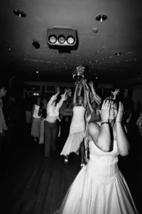 The bouquet flies through the air as guests reach up to catch it. Bride’s bouquet in mid-air as wedding guests reach up to catch it.
