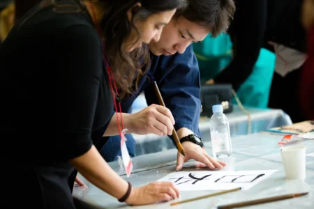 Conference attendees learn the Japanese art of calligraphy during a hands-on demonstration led by calligraphy students from Ritsumeikan University. Japanese Calligraphy Demonstration by Ritsumeikan Students