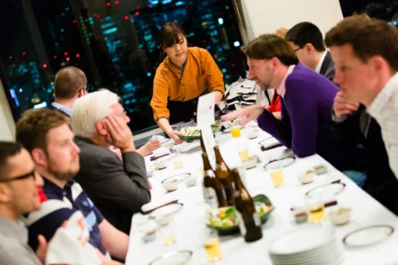 Conference delegates enjoy traditional Japanese food and sake during a conference dinner overlooking the Osaka skyline. Conference Dinner with Osaka Skyline